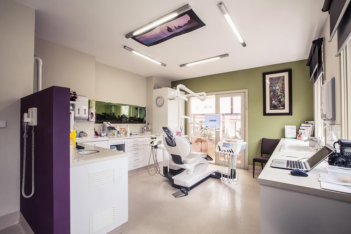 A photo of a high tech dental office with a TV on the ceiling.